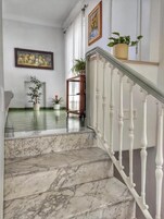 Eine Marmortreppe mit weißen Balustraden führt zu einer Zwischenebene.