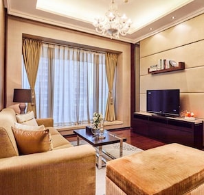A modern living room with a sofa, ottoman, and a flat-screen TV.
