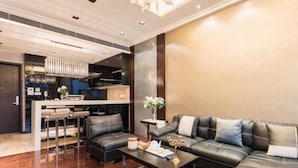A modern living room with a black leather sofa, a coffee table, and a chandelier. - Guangzhou Y&W Service Apartment (Guangzhou)