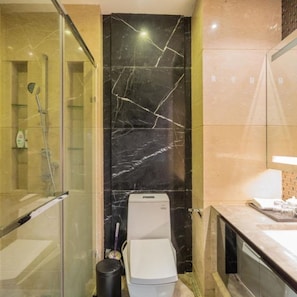 A modern bathroom with a glass shower enclosure, a toilet, and a sink area.