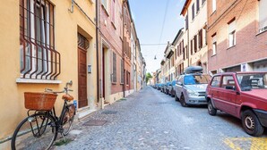 Une rue pavée bordée de voitures garées et d’immeubles.