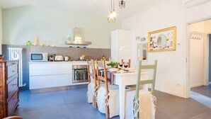 Une cuisine moderne avec des meubles blancs, une table à manger avec des chaises et un four à micro-ondes.