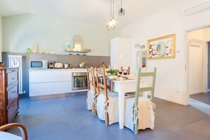 A modern kitchen with white cabinets, a dining table with chairs, and a microwave.