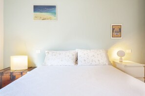A bed with white bedding, two bedside lamps, a nightstand, and a framed picture on the wall.