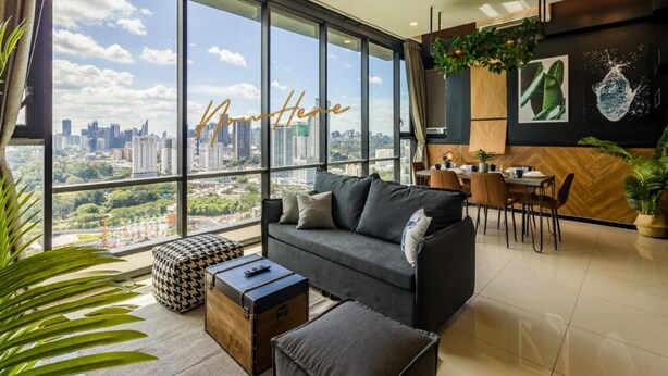 Uma sala de estar moderna com uma janela grande, um sofá, uma mesa de centro e um espaço de refeições com cadeiras e uma mesa.