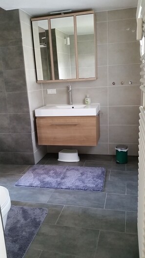 Une salle de bain moderne avec un grand miroir, un lavabo et des toilettes.