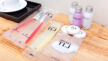 Toiletries including a toothbrush, shampoo, and a shower cap, arranged on a wooden surface.