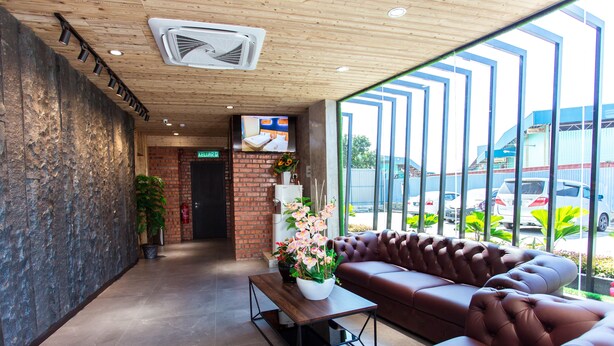 A modern lobby with a leather sofa, a wooden coffee table, and a large window with a view of parked cars. - TLJ Hotel (Pelabuhan Klang)