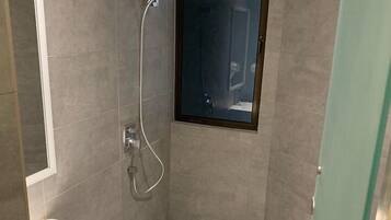 A modern bathroom with a shower, a sink, and a glass door.