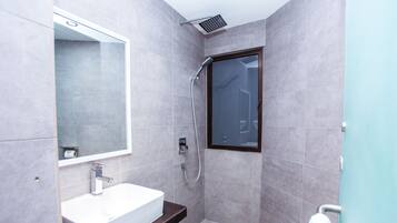 Ein modernes Badezimmer mit Waschbecken, Spiegel und Duschbereich.
