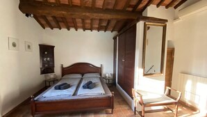 Ein Schlafzimmer mit einem hölzernen Bett, einem Sessel und einem großen Spiegel.