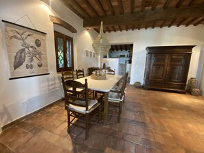 Un coin repas avec une table et des chaises en bois, un luminaire suspendu et un grand tableau au mur.