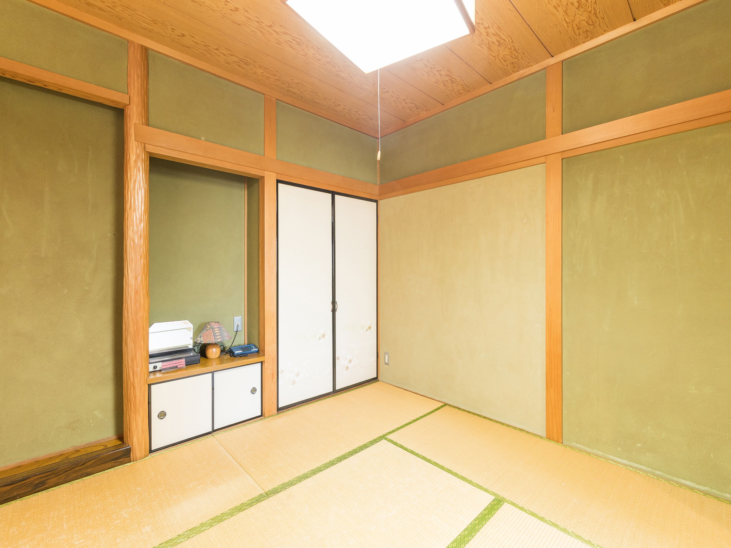 A room with tatami flooring, a sliding door, and a small table with items on it.