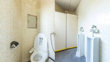Baño con inodoro, orinales y secamanos.