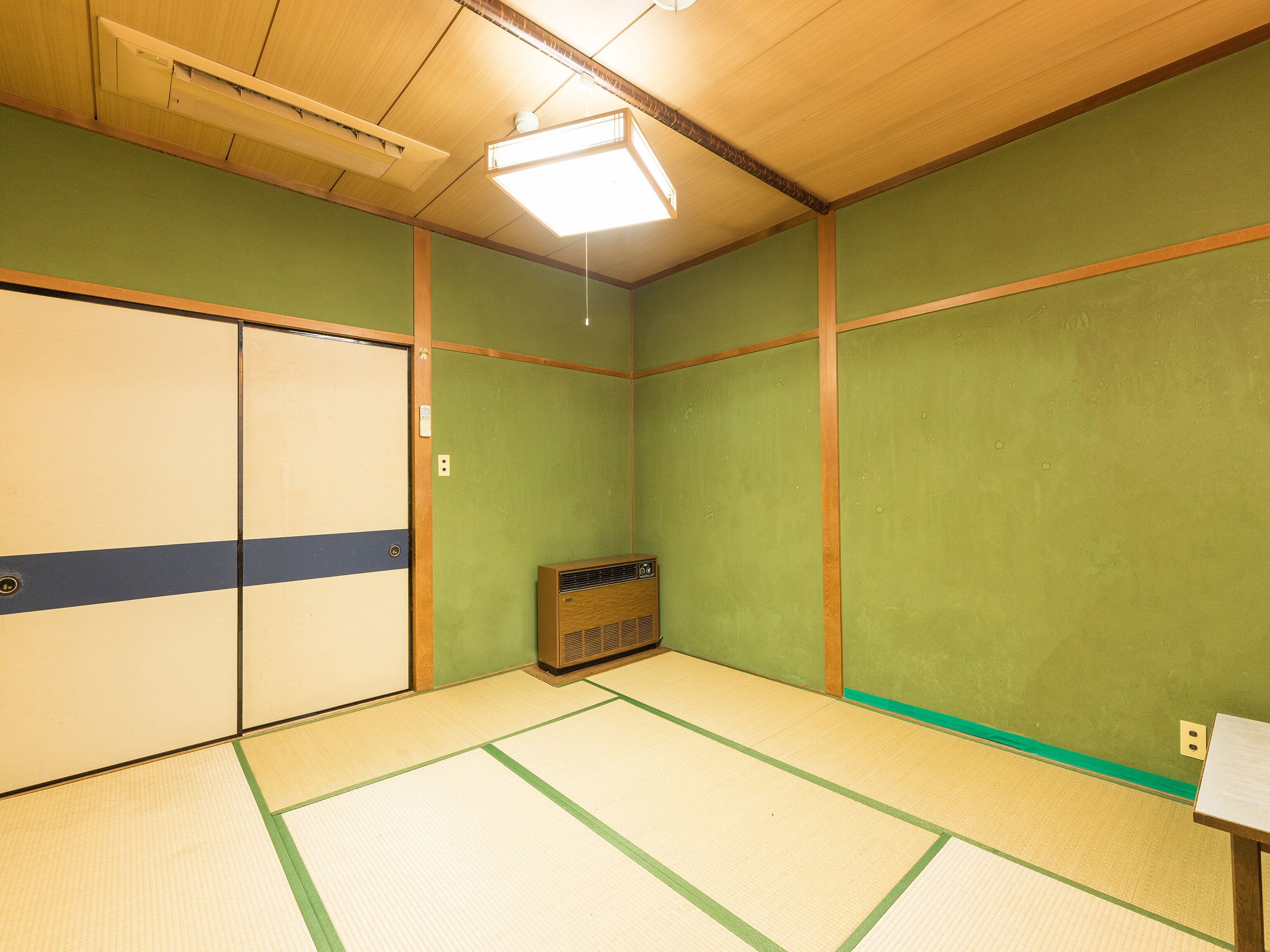 Ein Zimmer mit Tatami-Boden, einem traditionellen japanischen Heizkörper und einer Schiebetür.