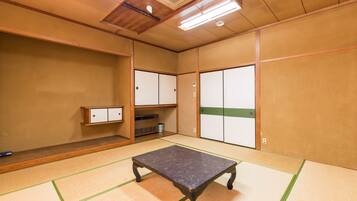 A tatami mat room with a tatami mat table, wooden cabinets, and a ceiling vent.