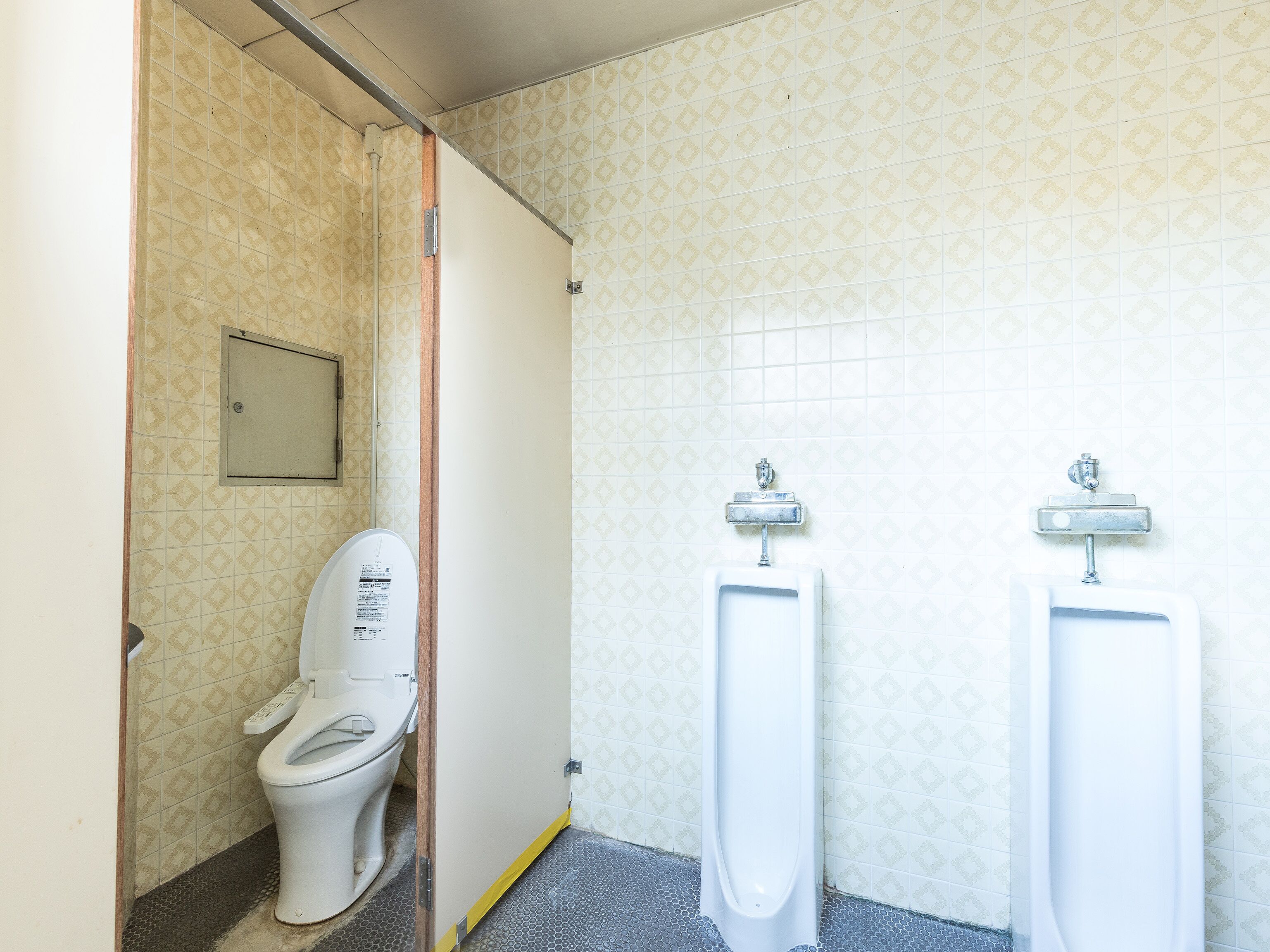 Baño de hombres con inodoro y dos orinales.