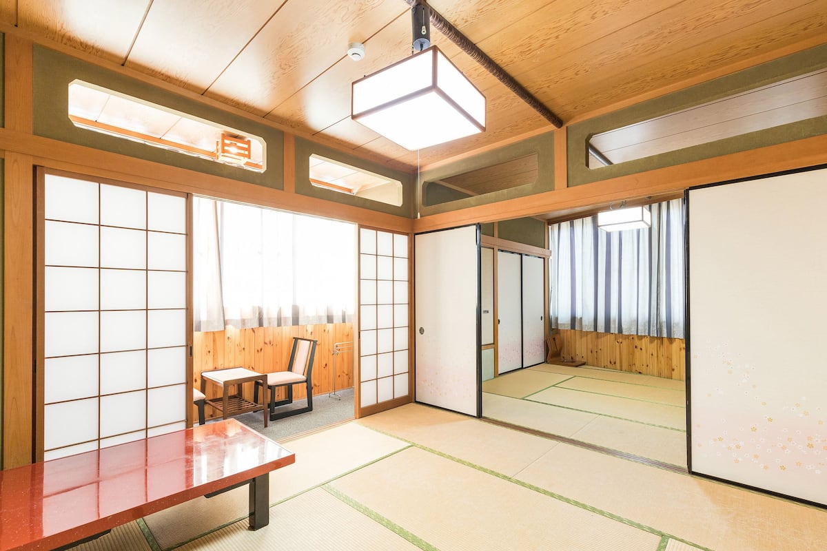 A traditional Japanese room with tatami flooring, a low wooden table, sliding doors, and a large mirror.