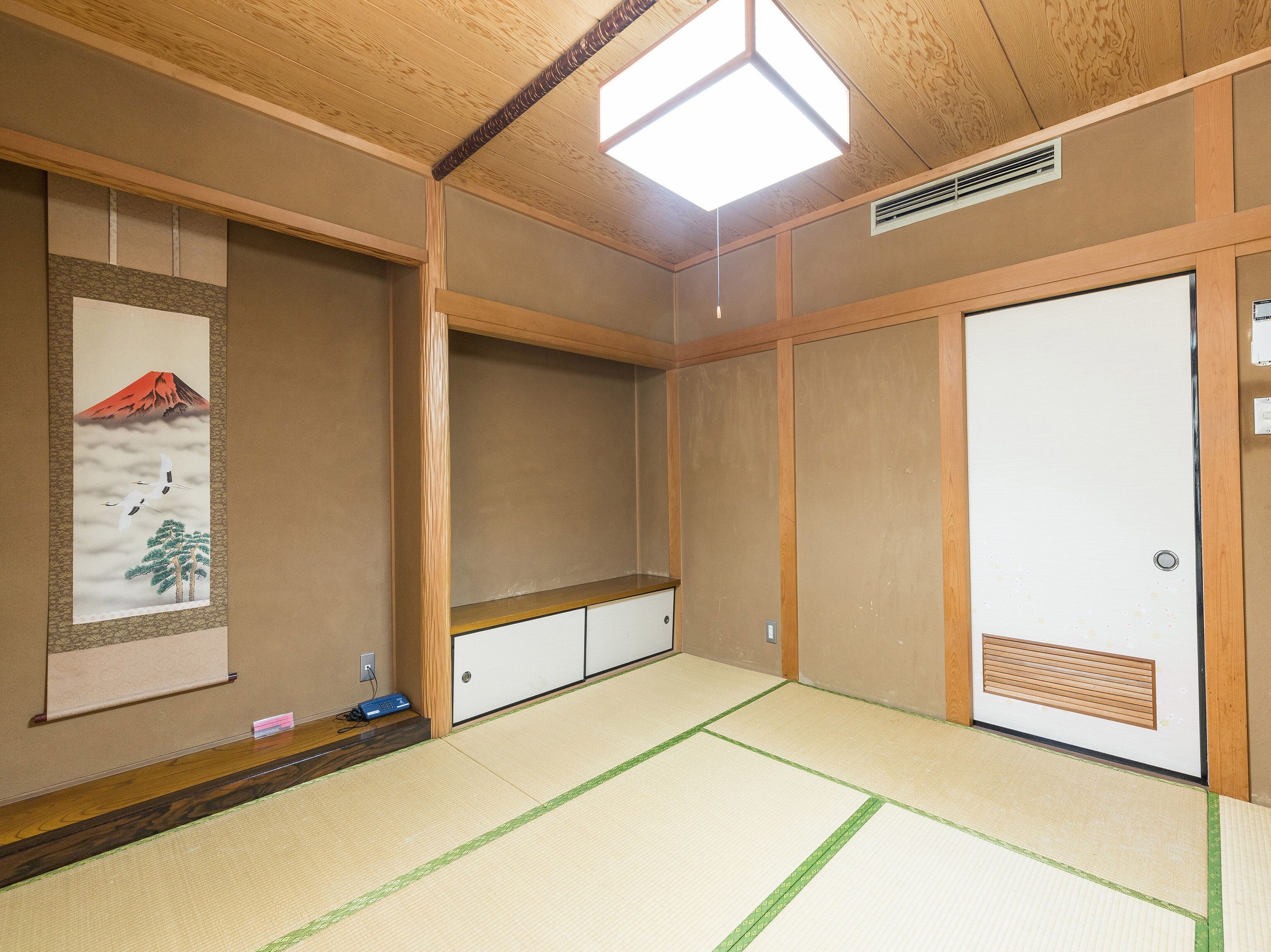 A traditional Japanese room with tatami flooring, a shoji screen with a mountain and crane artwork, and a sliding door.