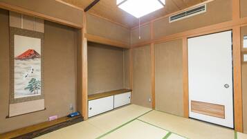 A traditional Japanese room with tatami flooring, a shoji screen with a mountain and crane artwork, and a sliding door.