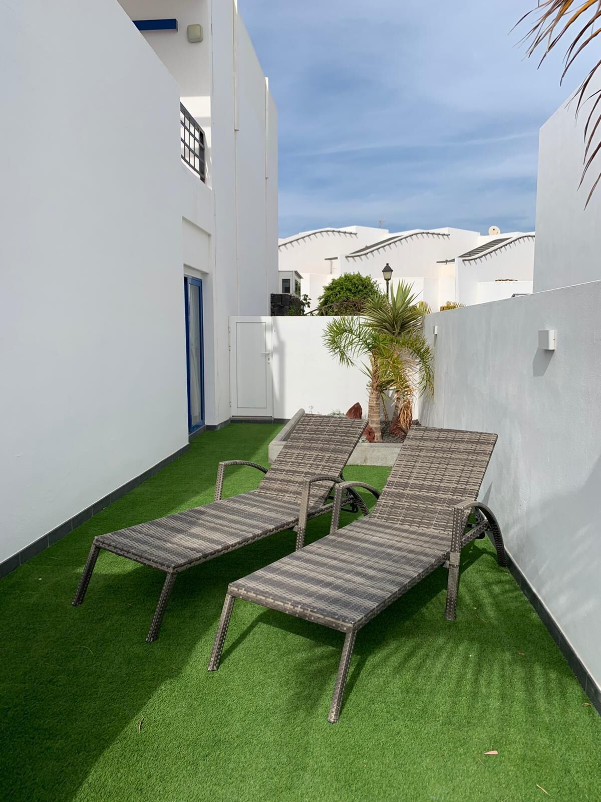 Une terrasse sur le toit, avec deux fauteuils de jardin en osier et un revêtement de sol en gazon synthétique.