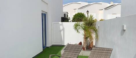 A rooftop terrace with two wicker lounge chairs and artificial grass.