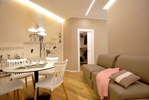 A modern living room with a dining area, a sofa, and a coat rack.