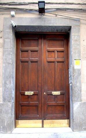 A double wooden door with a brass handle, set in a stone building.