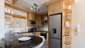 Een moderne keuken met een zwart granieten aanrecht, roestvrijstalen apparatuur, houten kastjes en een inbouwoven.