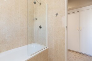 Une salle de bain moderne avec une douche à parois de verre, une baignoire blanche et un placard à portes doubles.