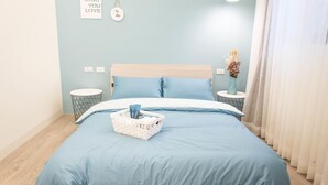 A bedroom with a bed, two bedside tables, a wall with a framed picture, and a window with curtains.