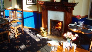 A cozy room with a fireplace, wooden furniture, and a table set for dining.