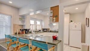 A modern kitchen with a central island, wooden bar stools, and a refrigerator.