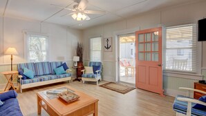 A living room with a sofa, armchair, coffee table, and a door leading to an outdoor area.