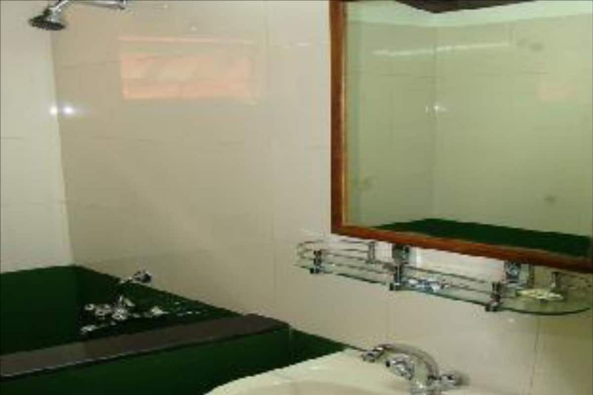 A bathroom with a sink, mirror, and green bathtub.