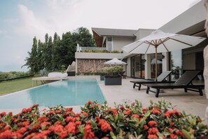 A modern poolside area with lounge chairs and umbrellas, surrounded by greenery and a clear sky. - White Monkey Villa - Private Pool & Jacuzzi (Langkawi)