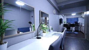 A modern living room with a white sofa, a large mirror, a desk with a laptop, and a potted plant.