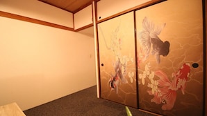 Ein traditioneller japanischer Raum mit Tatami-Bodenbelag, niedriger Holzdecke und Schiebetüren mit floralen und Fischmotiven.