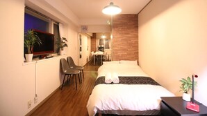 Ein kleines Hotelzimmer mit Bett, Schreibtisch, Stuhl und Fernseher.