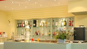 Zona de bar con estanterías llenas de botellas de licor, vasos y una planta en maceta.