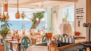 A restaurant with wooden furniture, a view of the sea, and a menu on the wall. - The Sea Club (Capdepera)