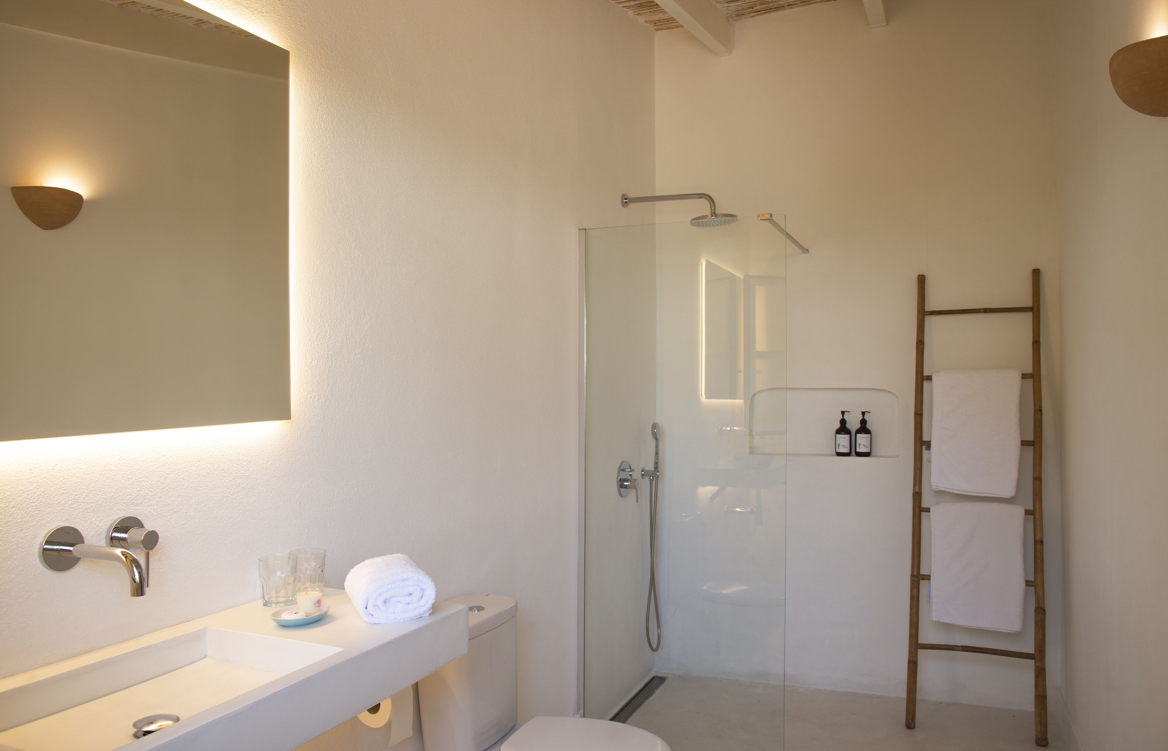 A bathroom with a glass-enclosed shower, a white sink, and a mirror.