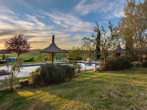 A serene outdoor setting with a pool, lounge chairs, and a gazebo.