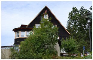 Un bâtiment noir avec un toit triangulaire, une antenne parabolique et une autre antenne parabolique visible sur le toit.