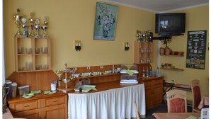 A dining area with a buffet setup, wooden cabinets, and a television mounted on the wall. - Zum Harzer Jodlermeister (Thale)