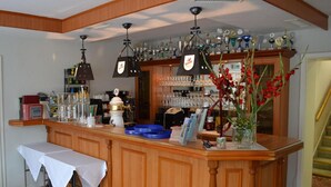 A bar area with a wooden counter, hanging lights, a variety of glassware, and a display of trophies. - Zum Harzer Jodlermeister (Thale)
