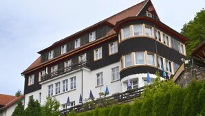 A multi-story building with a black and white facade, multiple balconies, and a red-tiled roof. - Zum Harzer Jodlermeister (Thale)