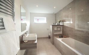 A modern bathroom with a large bathtub, a separate sink, and a vanity.