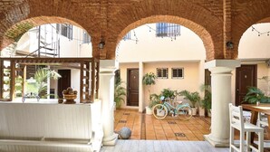 An outdoor patio area with arches, a bicycle, and potted plants. - Relaxing Getaway in a Colonial Hotel
 (Zona colonial)