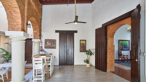 A spacious interior with a dining area, a ceiling fan, and a large wooden door. - Relaxing Getaway in a Colonial Hotel
 (Zona colonial)